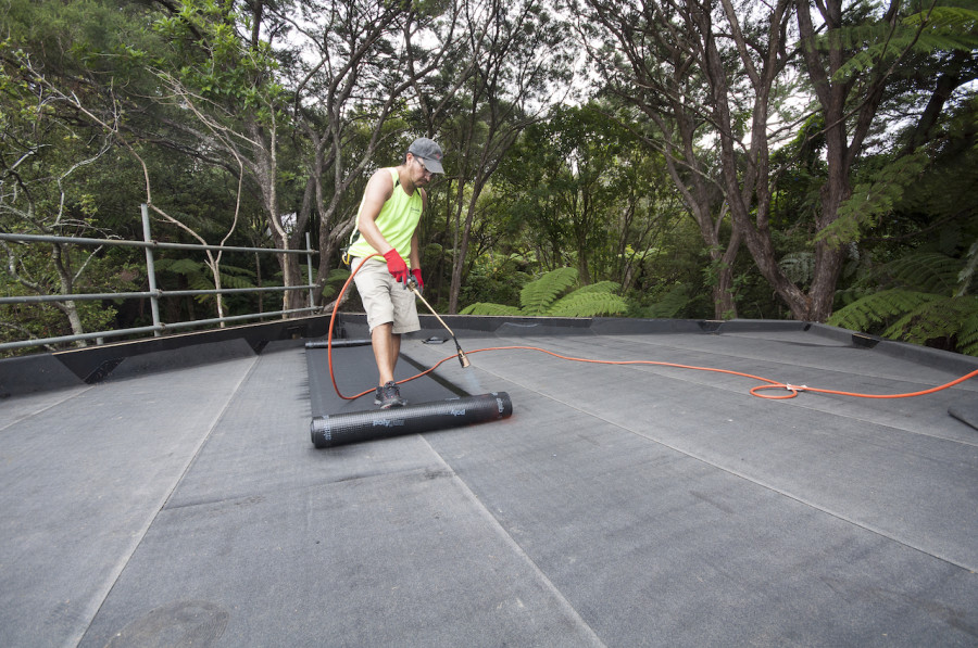 The cap sheet is torched on, basically welding to down to the base sheet below. You can see how the two layers are offset of each other, making the roof completely waterproof.